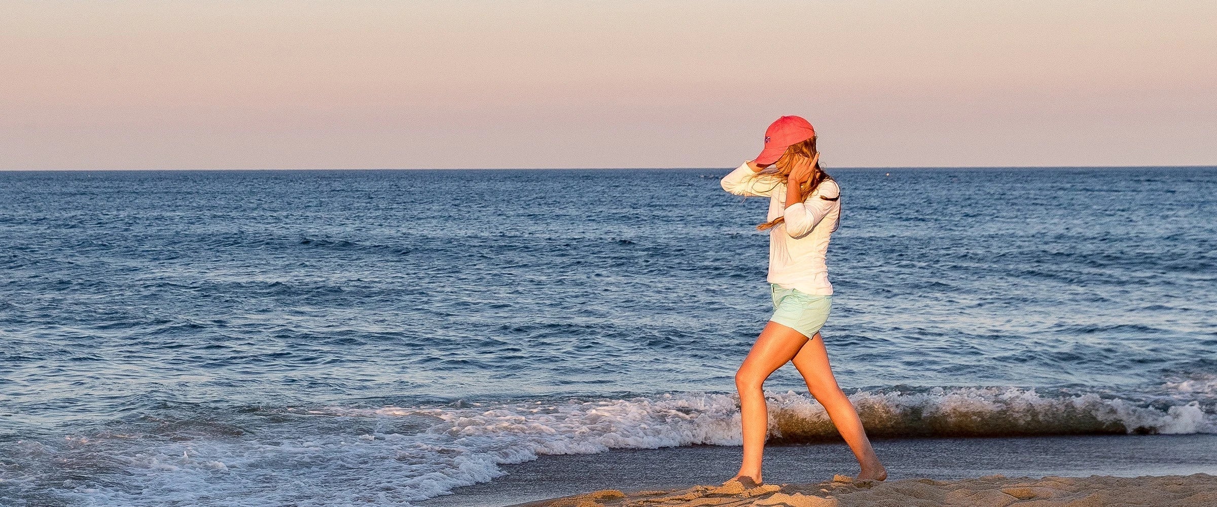 Girl walking on beach wearing Belted Cow Hat