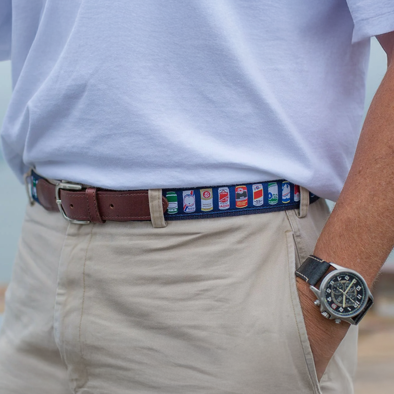 Person wearing a watch and Cheap Buzz Club Belt with a blurred beach background